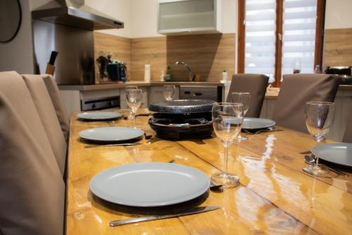 une table en bois avec des assiettes et des verres dans l'établissement Logement cosy 4/6 pers - quartier historique calme, à Cauterets