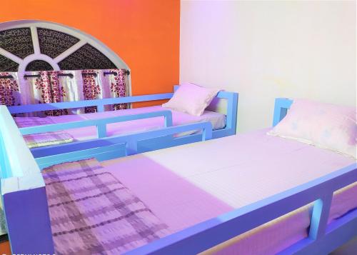 Habitación con 2 camas y pared de color naranja. en Criston Home stay, en Madurai