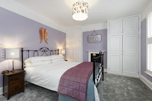 a bedroom with a large bed with purple walls at Pepperpot Cottage in Whitstable