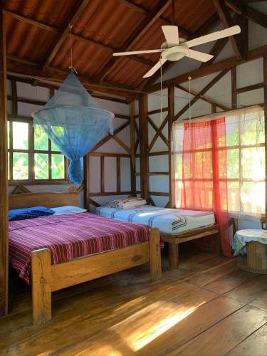 a bedroom with two beds and a ceiling fan at Casa de Colores in El Zonte