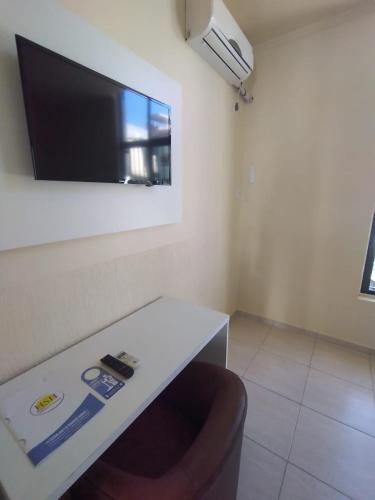 a room with a table and a tv on a wall at HsHotelaria - Filial Bombinhas in Bombinhas