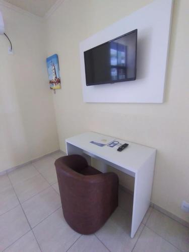 a white desk with a chair and a tv on a wall at HsHotelaria - Filial Bombinhas in Bombinhas