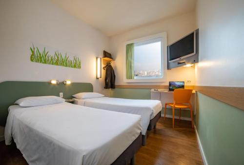 um quarto de hotel com duas camas e uma secretária e uma janela em ibis budget SP Frei Caneca em São Paulo