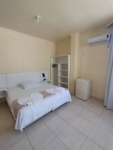 a bedroom with a white bed and a tiled floor at HsHotelaria - Filial Bombinhas in Bombinhas