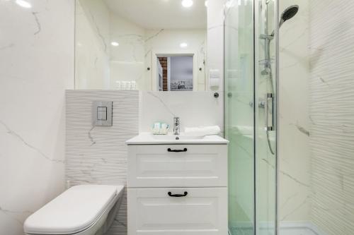 a white bathroom with a sink and a shower at Happy Stay Apartments Osiek in Gdańsk