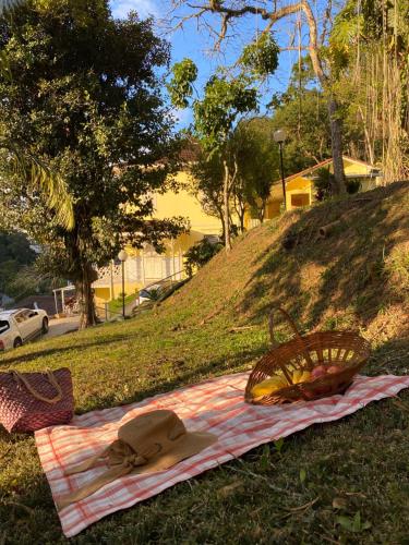 a picnic blanket with a basket and a hat on it at Pousada Princesa Isabel - Visconde in Petrópolis