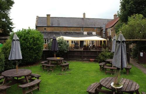 a group of picnic tables and umbrellas in a yard at The Fleur-De-Lis Hotel in Chiselborough