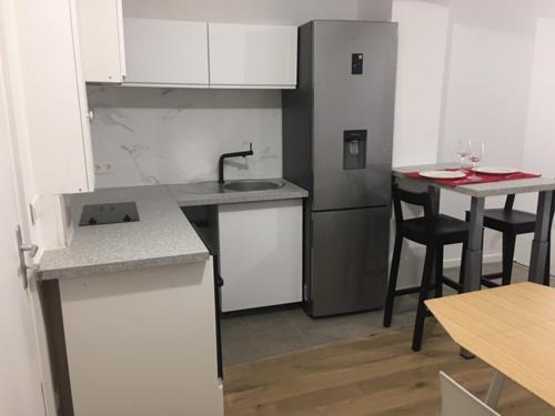 a kitchen with white cabinets and a table and chairs at COSY PUTEAUX QUAI DION BOUTOn in Puteaux