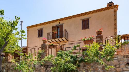 a building with balconies and flowers on a stone wall at Casale Margherita Turismo Rurale in Pollina