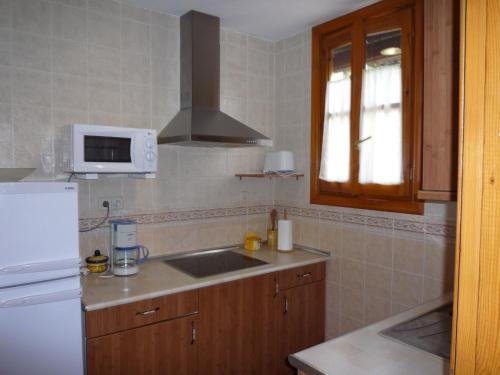 eine Küche mit einer Spüle und einer Mikrowelle in der Unterkunft Casa Rural El Molino de Alocén in Alocén