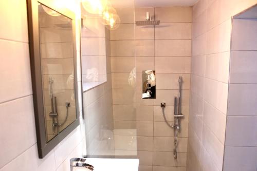 La salle de bains est pourvue d'une douche, d'un lavabo et d'un miroir. dans l'établissement 1 The Cottage, Studio Apartment, Ye Olde Barn Apartments, à Stamford