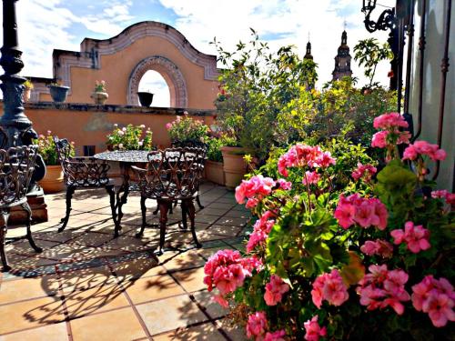 een patio met een tafel, stoelen en bloemen bij Hotel Hacienda los Narcisos in San Juan de los Lagos