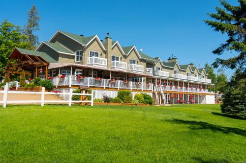 a large house with a lawn in front of it at Pourvoirie du Lac Blanc in Saint-Alexis-des-Monts