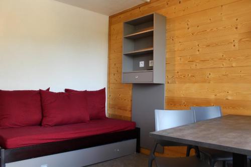 - un canapé rouge dans une chambre avec une table dans l'établissement travelski home select - Vue Pistes, à La Plagne