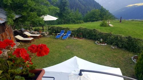 a backyard with a table and chairs and red flowers at HOME SWEET HOME in Antey-Saint-André