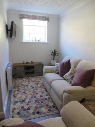 a living room with a couch and a window at Chapel Cottage in Oundle