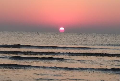 a sunset over the ocean with the sun in the horizon at TOSCANA HOME in Ravenna