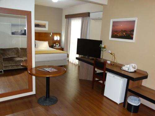a hotel room with a bed and a desk at Castel Plaza Hotel in Resende