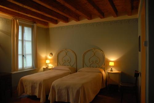 two beds in a bedroom with two lamps at Agriturismo La Costa in Crema
