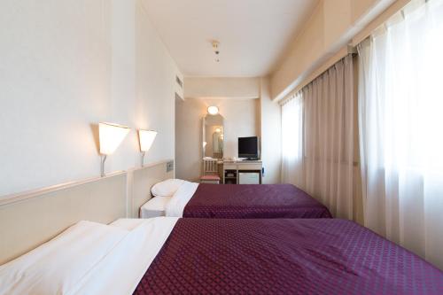 a hotel room with two beds and a window at Tabist Hotel Tetora Kitakyushu in Kitakyushu