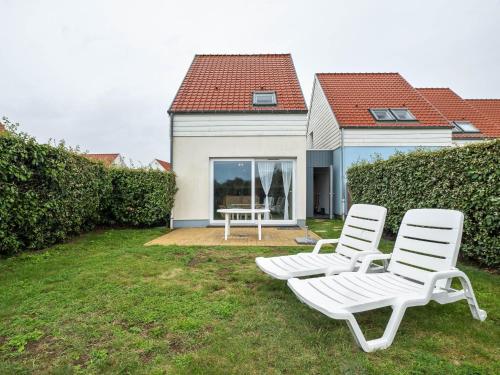 two white chairs sitting in the yard of a house at Cosy holiday home with garden in Wimereux in Wimereux