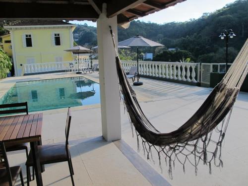 a hammock on a patio next to a pool at Pousada Princesa Isabel - Visconde in Petrópolis