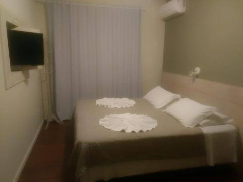 Pousada Porto do Arvoredo في فلوريانوبوليس: غرفة نوم مع سرير مع وسادتين بيضاء