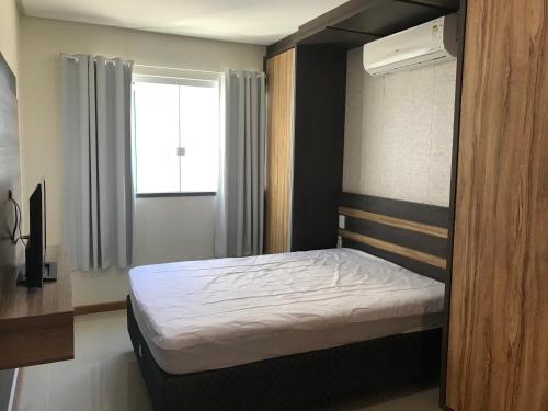 1 dormitorio con 1 cama en una habitación con ventana en Flores de Veneranda, en Bombinhas