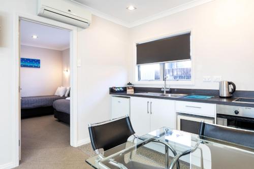 a kitchen with a glass table and a counter top at Beach Street Motel Apartments in New Plymouth