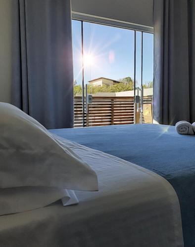 a bedroom with a bed and a large window at Pousada Suítes do Rosa in Praia do Rosa