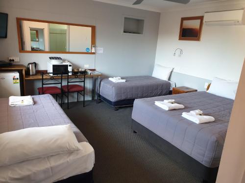 a hotel room with two beds and a desk at Civic Motel Grafton in Grafton