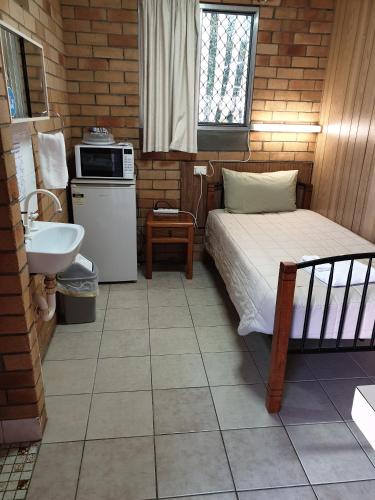 a small bedroom with a bed and a sink at Civic Motel Grafton in Grafton