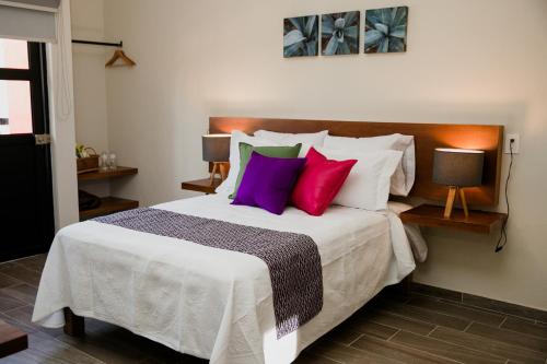 a bedroom with a large bed with colorful pillows at Casa MAYAHUEL x Santiago de Tequila in Tequila