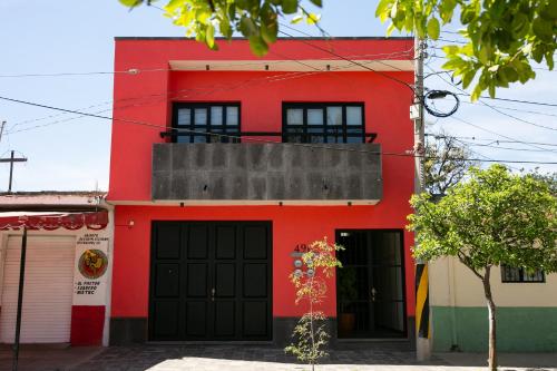 a red building with black doors and a balcony at Casa MAYAHUEL x Santiago de Tequila in Tequila