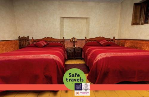 two beds in a room with a sign that says safe travels at Hotel del Carmen in Tlalpujahua de Rayón