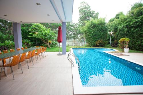 a swimming pool with chairs and a table and an umbrella at Bạch Yến T111-Happy Villa Đại Lải Resort in Vĩnh Phúc