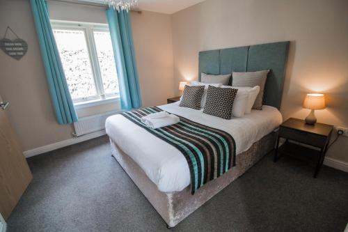 a bedroom with a large bed with blue curtains at Balmaha Lodges and Apartments in Balmaha