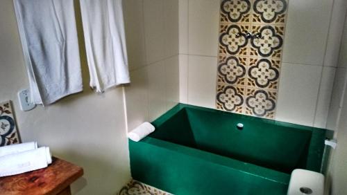 a bathroom with a green tub in a room at Sítio Flor das Águas in Lumiar