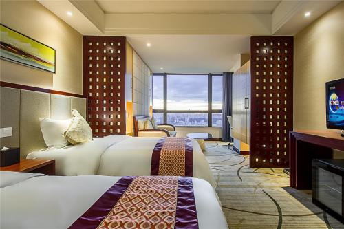 een hotelkamer met 2 bedden en een televisie bij Haikou Mingguang Shengyi Hotel (Previous Mingguang International Hotel) in Haikou
