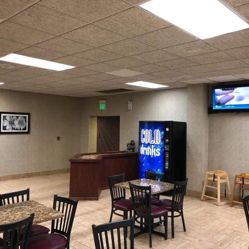 a dining room with tables and chairs and a television at Baymont by Wyndham Michigan City in Michigan City