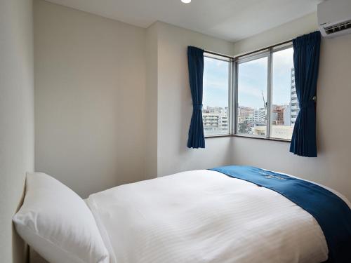 那霸的住宿－エナジックホテル山市 Enagic HOTEL YAMAICHI，卧室配有白色的床和窗户。