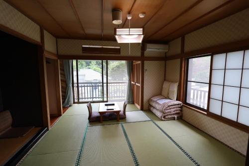 a room with a room with a table and windows at Onsen & Garden -Asante Inn- in Hakone