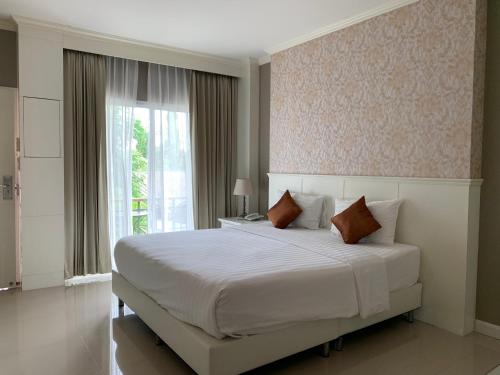 Un dormitorio con una gran cama blanca y una ventana en Homey Dormy Chiangrai, en Chiang Rai