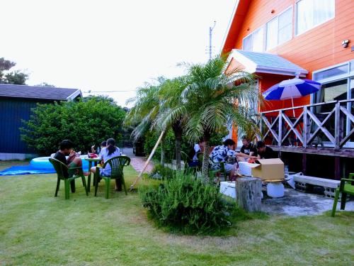 a group of people sitting at a table in a yard at 陽のあたる宿 サンセットパーム in Oshima