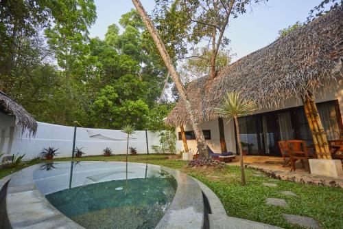 a house with a swimming pool in the yard at Xandari Pearl Beach Resort in Mararikulam