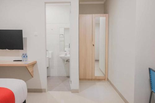 a bedroom with a bed and a bathroom with a sink at RedDoorz Plus near Soekarno Hatta Airport Taman Mahkota in Tangerang