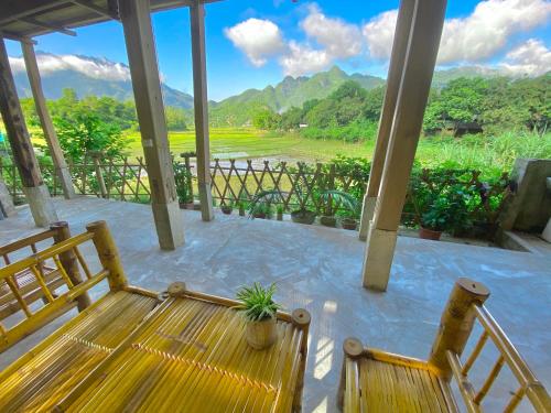 a porch with two benches and a view of the mountains at Meadow Mai Chau Homestay in Mai Chau