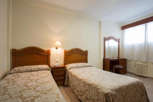 a hotel room with two beds and a mirror at Hotel Riviera in Córdoba