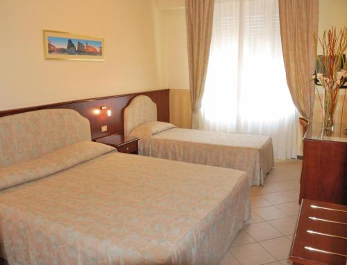 um quarto de hotel com duas camas e uma janela em Hotel Olimpic em Castel Maggiore