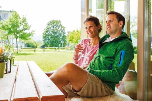 a man and a woman sitting on a bench at Hotel Alpenblick in Ohlstadt